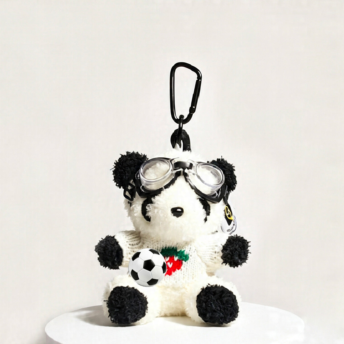 Panda plush bag charm in white strawberry-print sweater holding a miniature soccer ball