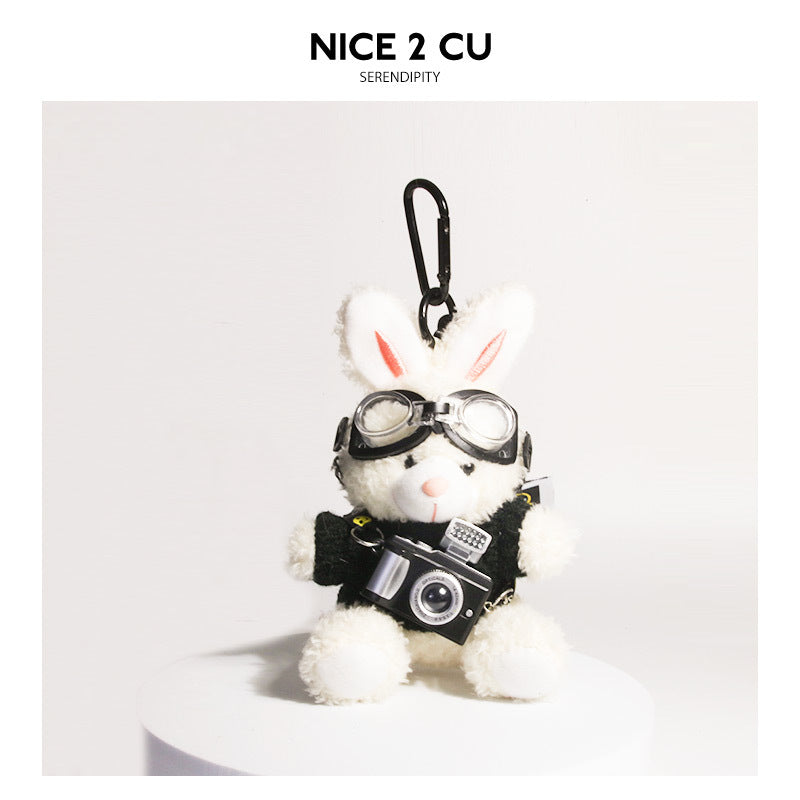 White plush rabbit keychain wearing black-and-white heart-pattern sweater with goggles and camera charm