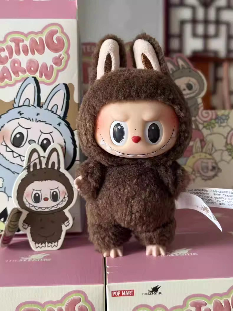 The Labubu Secret Edition “Chestnut Cocoa” Plush Keychain – Pop Mart Standing Brown Bunny by Kasing Lung from POP MART stands on pink boxes, surrounded by matching character illustrations and branded packaging.