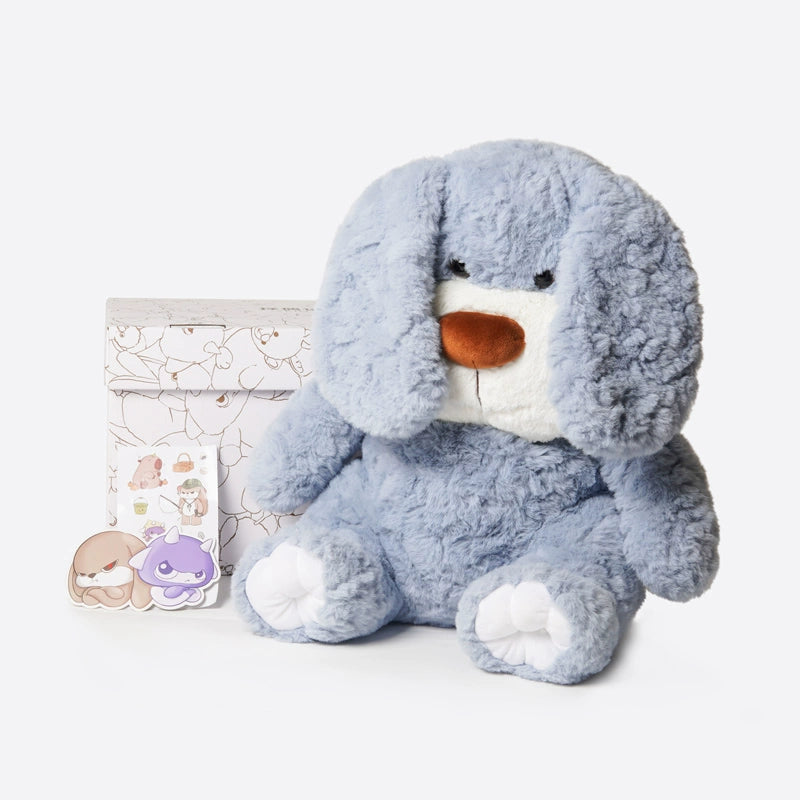 The ZEIO Charlie Dog Plush Toy 50cm, a soft large stuffed pup with floppy ears, sits before a floral-patterned box with two character pins and a sticker sheet—ideal as a cuddly companion or cute nursery decor.