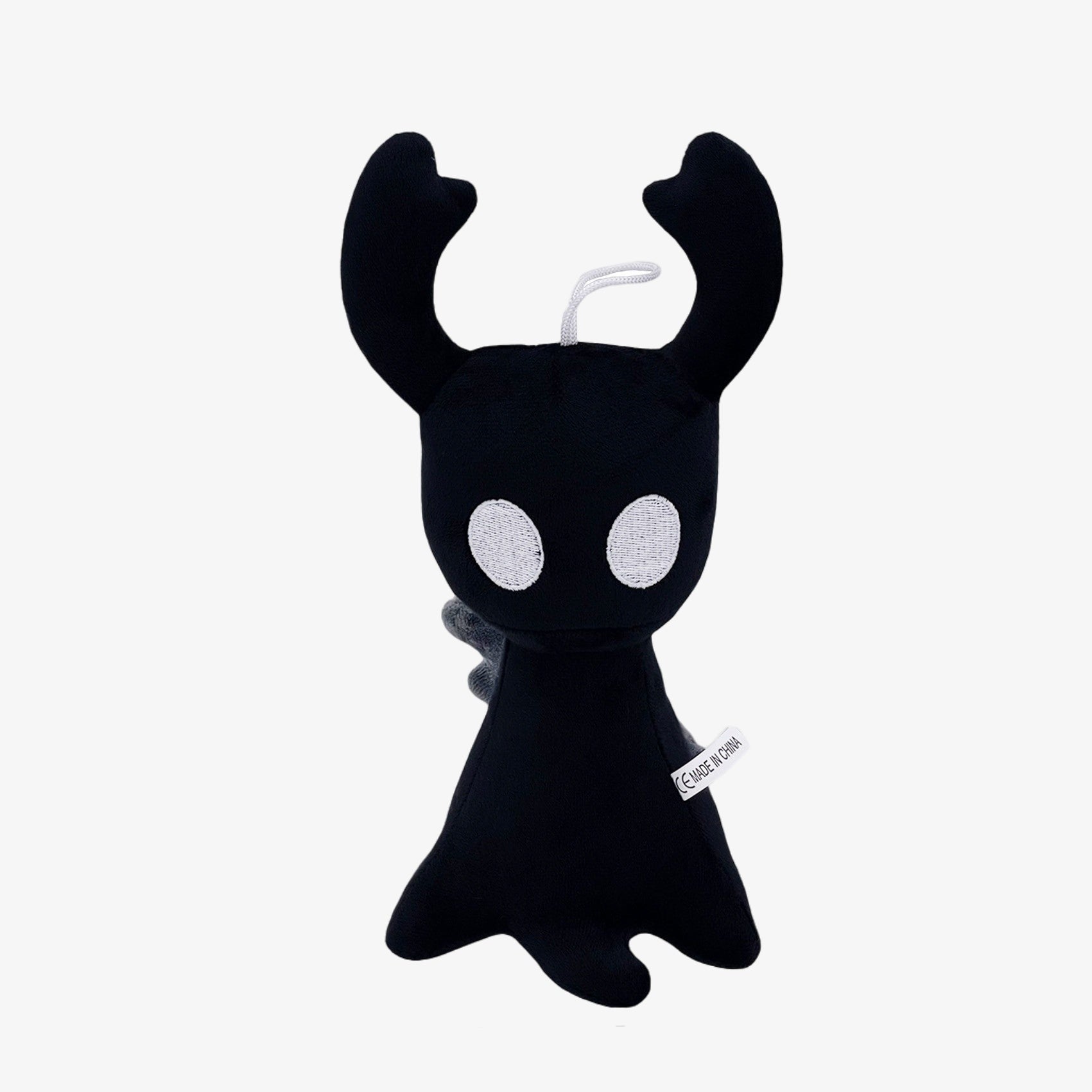 The Officially Licensed Hollow Knight Plush Doll by Hollow Knight features a black shadow horned bug character with white eyes, soft fabric, and a side tag. This 10.24-inch collectible stuffed toy is shown against a plain white background.