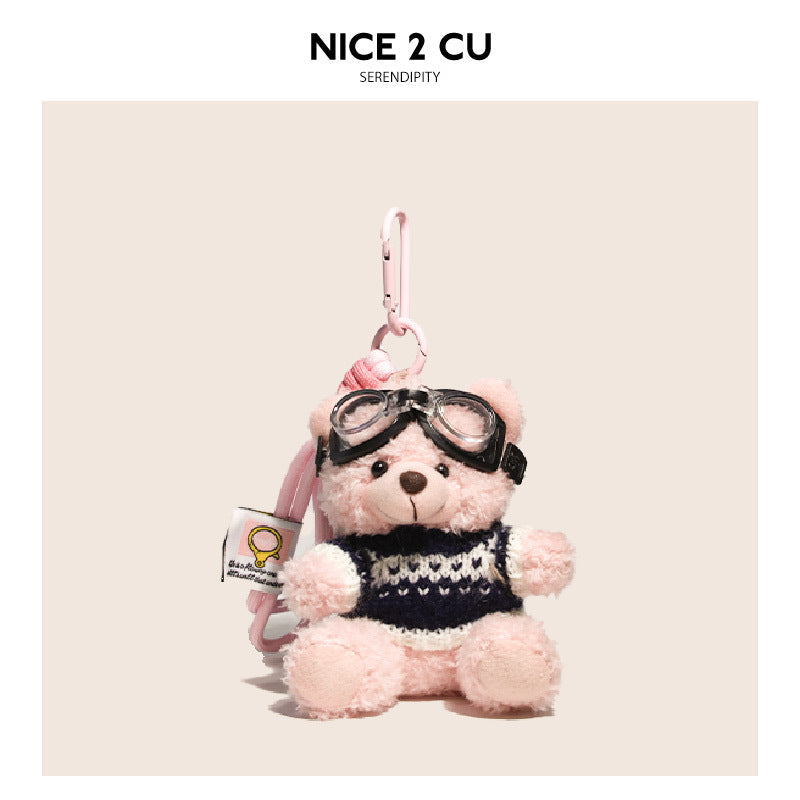 Pink teddy bear plush keychain in a dark navy knitted sweater with light neckline pattern and black goggles