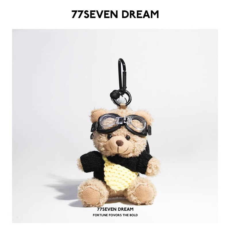 Beige plush teddy bear keychain in black knit sweater with yellow knitted front pouch accent and aviator goggles