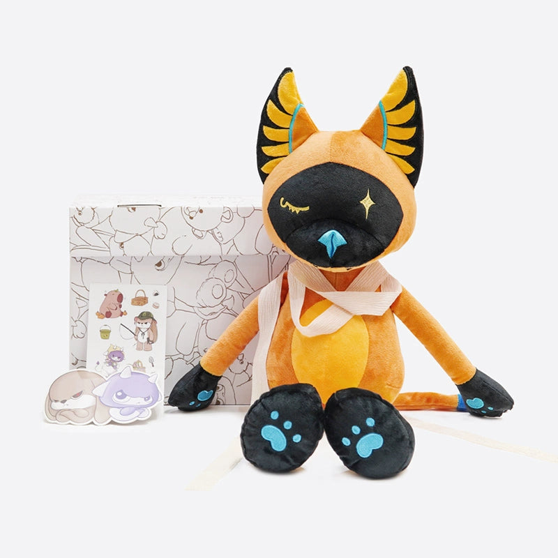 The ZEIO Egyptian Cat Plush Toy – Mystical Soft Stuffed Animal with Star Eyes rests in front of a patterned box, accompanied by several cartoon stickers.