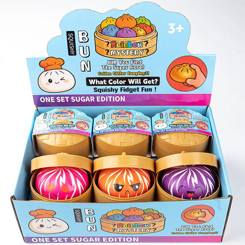 A display box of ZoDoll Rainbow Mystery Squishy Bun Fidget Toys with Steamer – Sugar Edition, shaped like colorful dumplings in round containers, shown on a playful gradient background. Suitable for ages 3 and up.