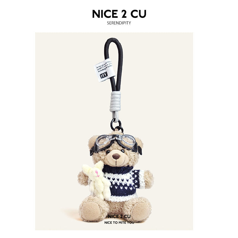 Beige plush teddy bear keychain in navy-and-white striped knit sweater with aviator goggles, holding a white rabbit