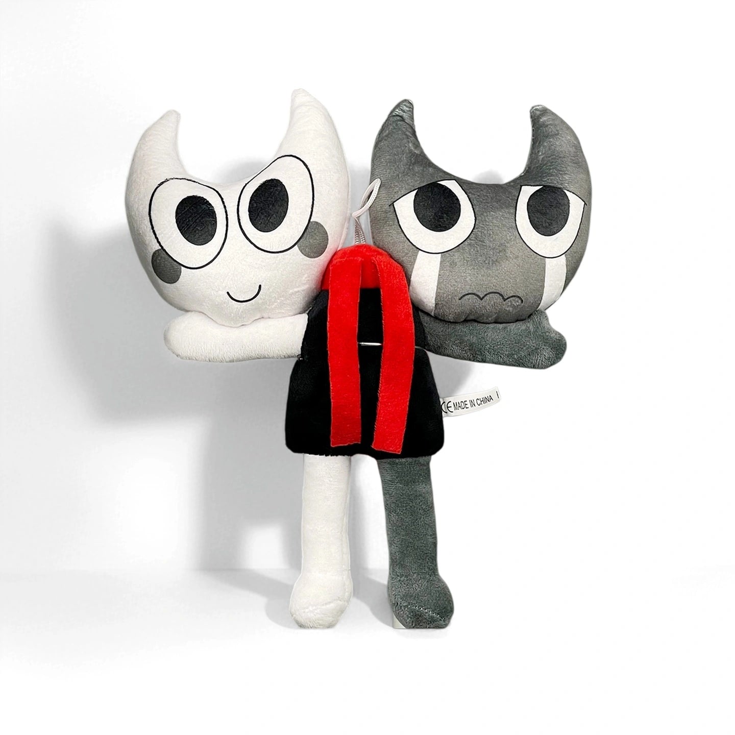 From Dandy's World, this plush from the Dandy's World Plush Collection features two individually sold character dolls—one white and cheerful, one gray and sad—joined together with a red and black accessory.