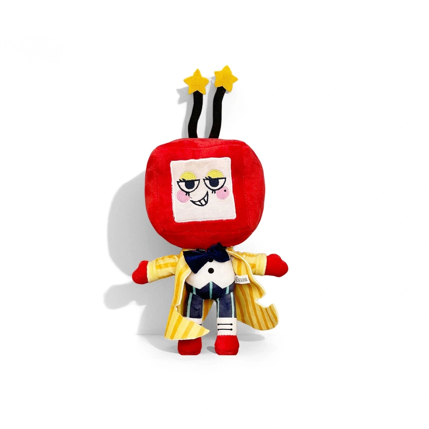 From the Dandy's World Plush Collection, this soft stuffed toy features a red, square head with a mischievous face, black antennae topped with yellow stars, and a yellow striped robe over blue pants and a bow tie.