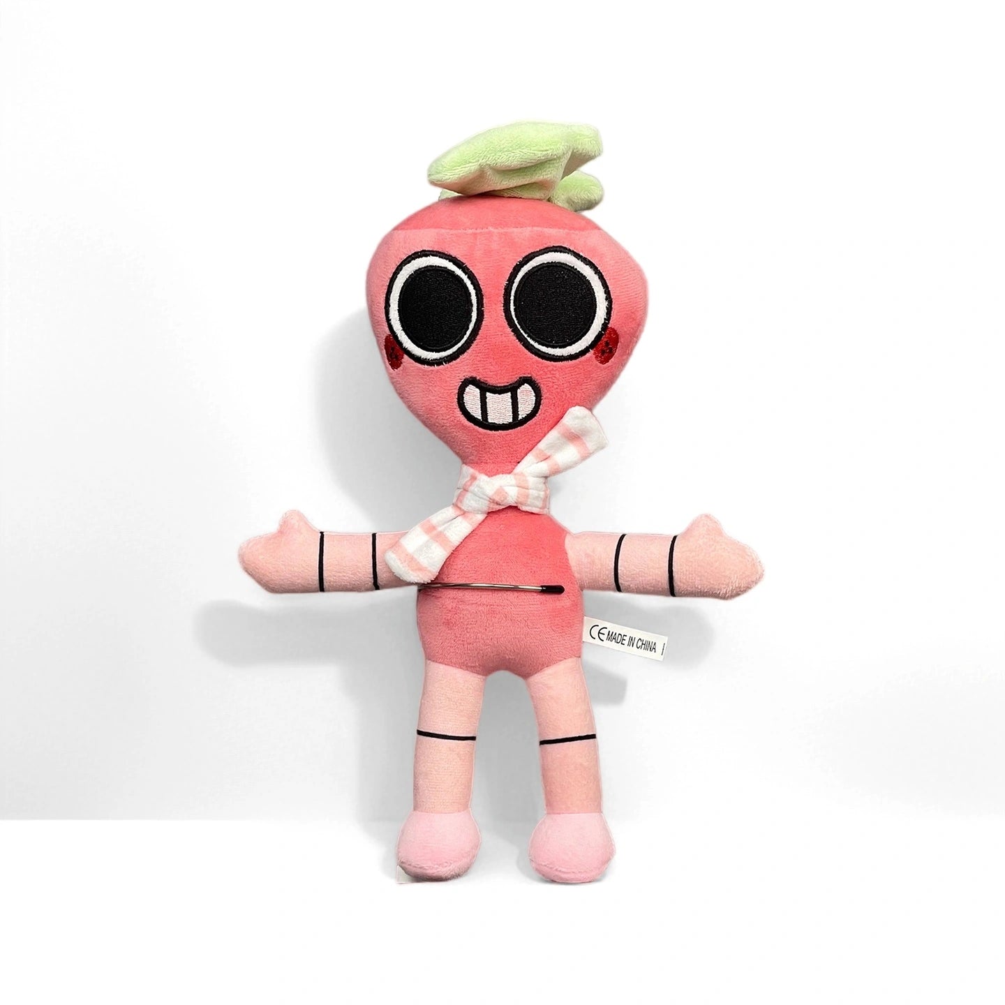 From Dandy's World Plush Collection, this pink radish plush features a smiling face, large black eyes, a plaid bow tie, and green leaf top. Sold individually by Dandy's World; perfect collectible for fans. Set on a plain white background.