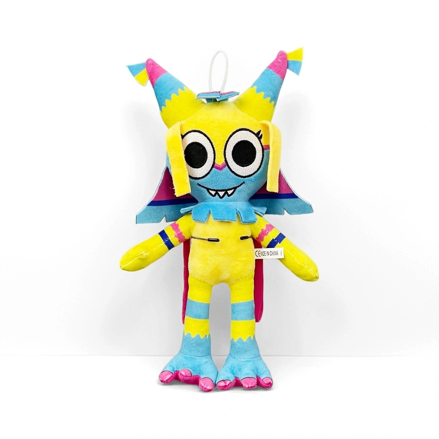 A soft plush toy from Dandy's World Plush Collection features yellow, blue, and pink stripes, big round eyes, pointed ears, and a wide smile. Each collectible character is sold individually by Dandy's World.