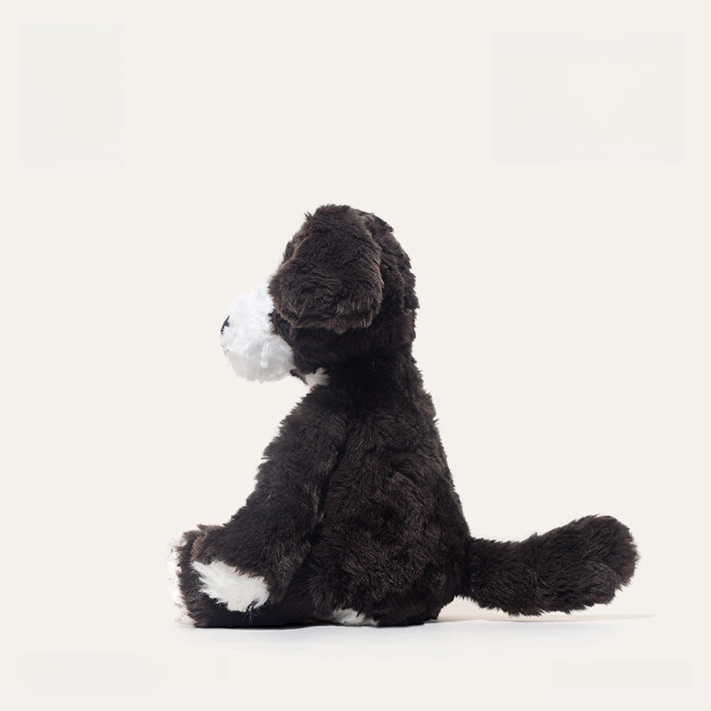 The JOOKI 24cm Black and White Puppy Plush Toy, a soft stuffed dog with floppy ears, sits upright in profile against a plain white background.