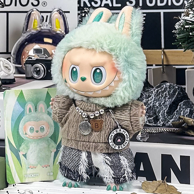 The ZoDoll Labubu Doll stands before its box in a mint-green bunny hood, large eyes, and a toothy grin, dressed in the Brown Cable Knit Sweater and Fringe Tweed Pants Outfit Set.