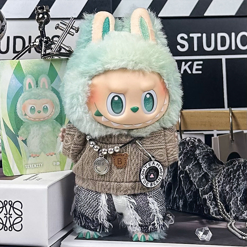 A ZoDoll Labubu doll wears the Brown Cable Knit Sweater and Fringe Tweed Pants Outfit Set, posed in a studio with props and a matching illustration, highlighting this charming ensemble.