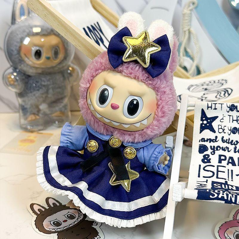 The ZoDoll Labubu Doll wears a navy blue Lolita dress with gold star and bow accents, topped with a wide grin and bunny hood, and stands beside a bunny-themed figure and decorative items.