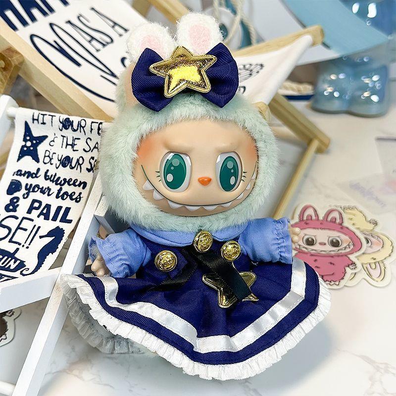The ZoDoll Labubu Doll wears a navy blue Lolita dress with gold stars and a bow, topped with a mint-green hood featuring bunny ears, and sits surrounded by celestial star accents and decorative objects.