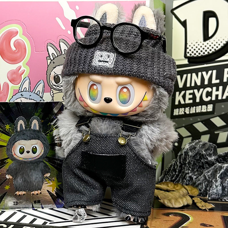 The ZoDoll Labubu Doll sports a gray fuzzy coat, dark denim overalls, and a knit beanie in this 3-piece set. It stands beside an illustrated card, with streetwear accents and a vibrant background adding extra flair.