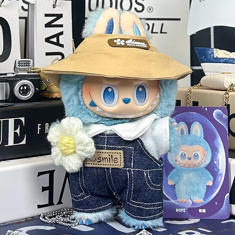 A ZoDoll Labubu plush toy wears the Denim Overalls and Wide-Brim Hat Outfit Set with Smile Patch, featuring bunny ears, a white shirt, and holding a flower beside a matching illustrated card.