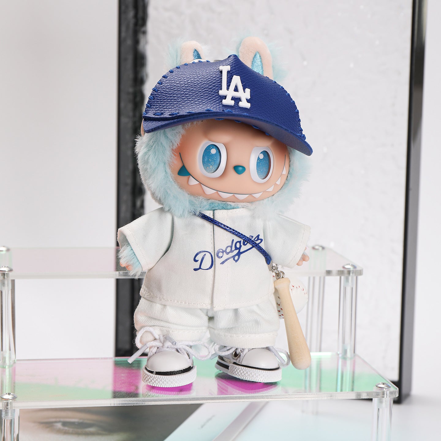 The ZoDoll Labubu Doll sports the Dodgers Baseball Jersey & LA Visor Cap Outfit Set, with large eyes and sharp teeth, standing on a display shelf.