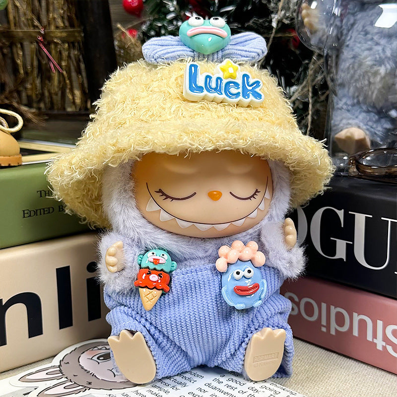 The ZoDoll Labubu Doll Lucky Bucket Hat and Corduroy Overalls Outfit Set features a plush Labubu wearing a fluffy yellow hat labeled “Luck” and blue corduroy overalls with colorful character pins, sitting on books.