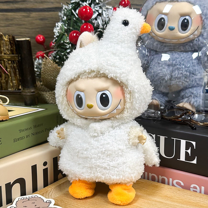 A ZoDoll Labubu White Fluffy Bird Kigurumi Doll Costume Set, featuring plush bouclé fabric and a large-headed plush doll, is displayed on a table with books and another doll in the background.