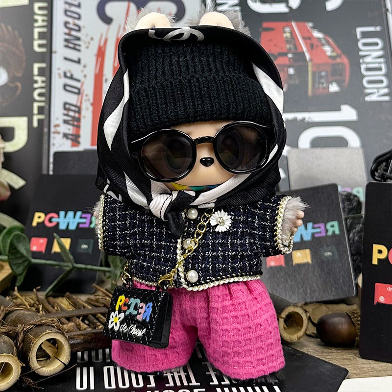 The ZoDoll Labubu is styled in the Designer Tweed Jacket and Hot Pink Pants Luxury Doll Outfit Set, featuring a black beanie, sunglasses, scarf, and purse, posed before a vibrant backdrop with colorful text and decorations.