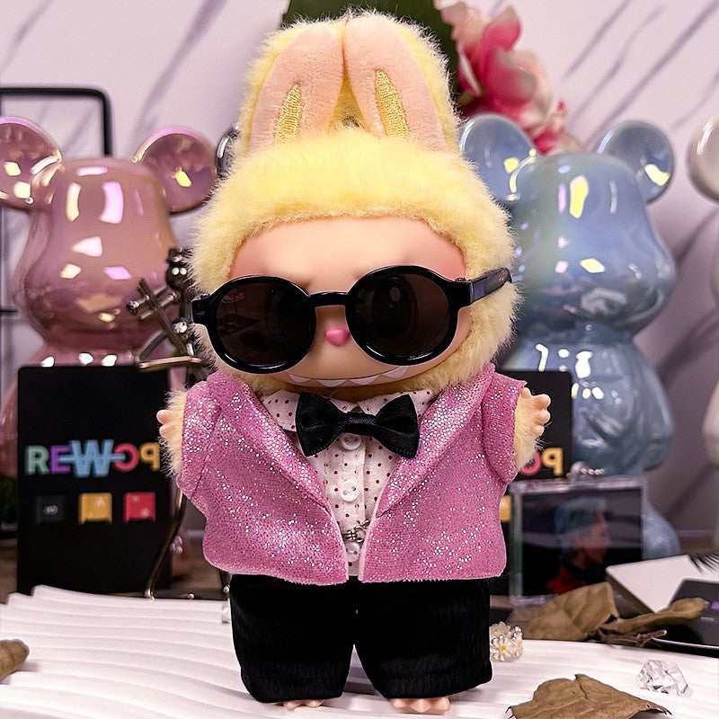 A ZoDoll Labubu Doll in a pink sequin blazer tuxedo outfit with a black bow tie stands before colorful bear-shaped figures, showcasing playful accessories and vibrant Pop Mart-inspired style.