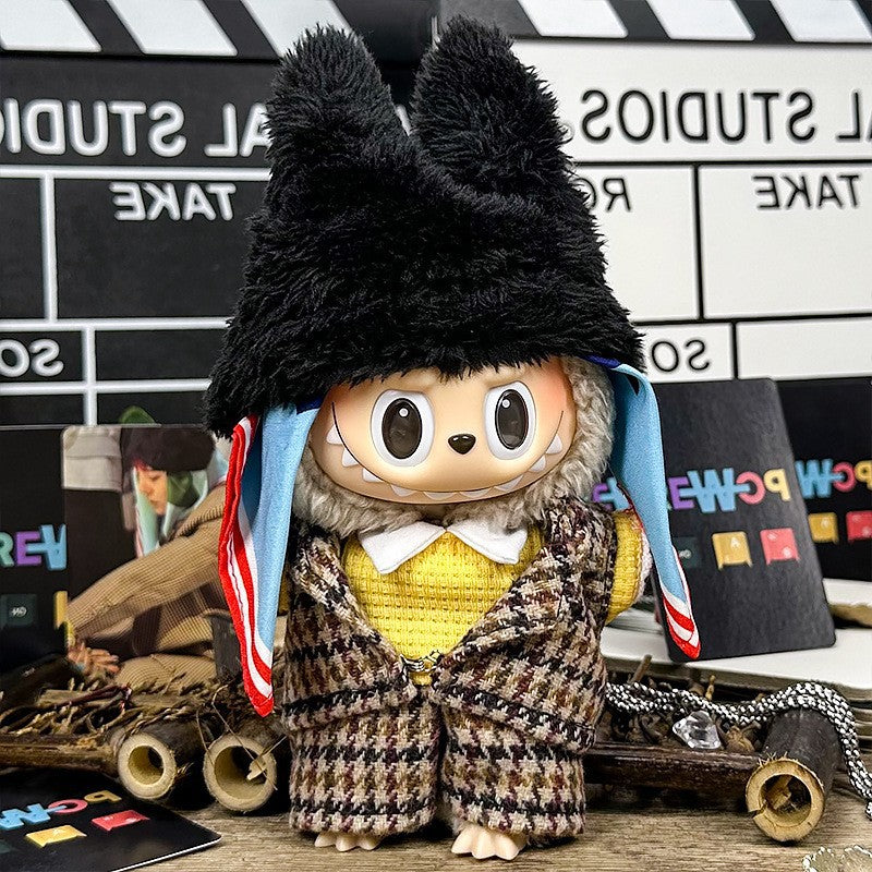 A ZoDoll Labubu Doll in a brown tweed plaid suit set and black fluffy bear hat stands among film studio props and equipment.