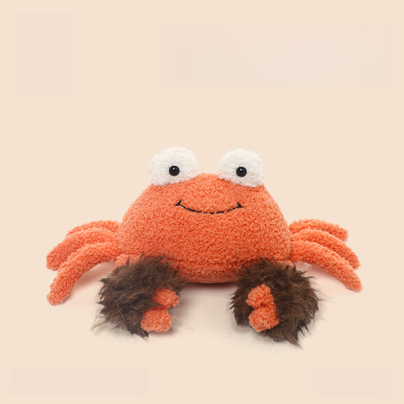 The JOOKI 23cm Orange Crab Plush Toy is a soft, smiling stuffed sea animal with large white eyes and fluffy brown claws, set against a plain light background.