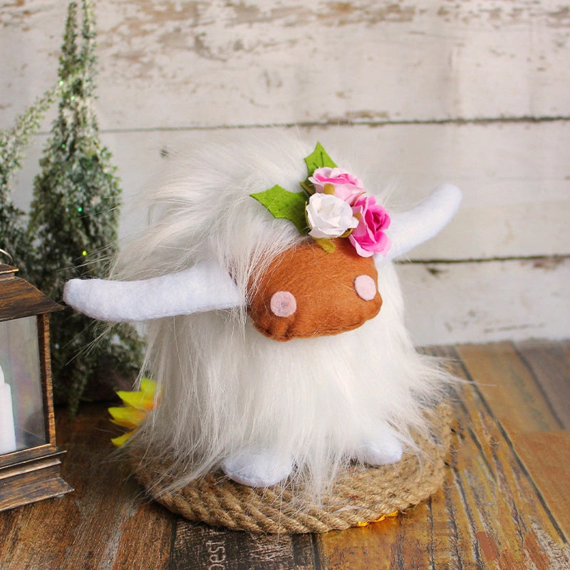 The ZoDoll Highland Cow Plush Toy with Pink Bow features soft long hair, felt horns, pink cheeks, and a floral crown. Shown in a cozy rustic setting, this plush comes in 6 colors for a charming decorative touch.