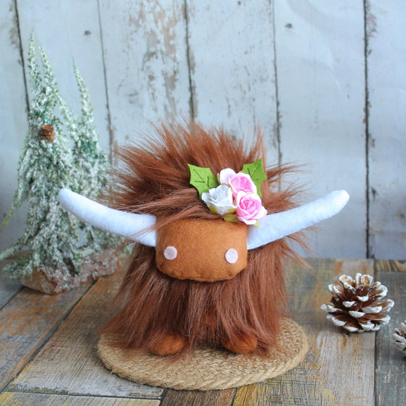The ZoDoll Highland Cow Plush Toy with Pink Bow features soft long hair and white horns. Available in 6 colors, it sits on a woven mat beside a pine cone and snowy tree, looking adorable with its signature pink bow.