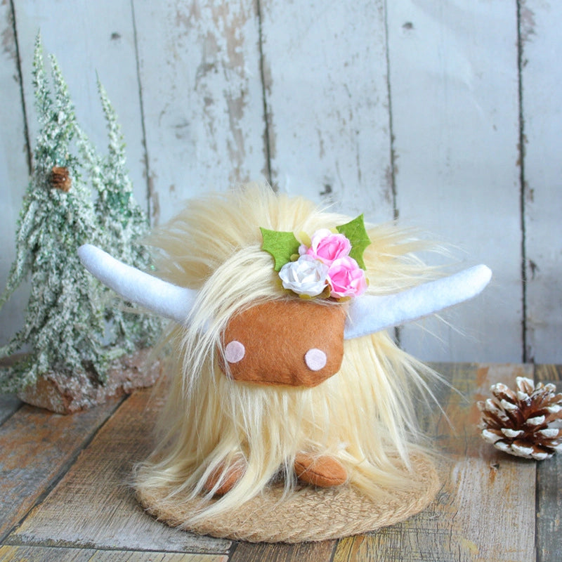 The ZoDoll Highland Cow Plush Toy with Pink Bow features soft long hair, white horns, and a flower crown. Available in 6 colors, it’s shown sitting on a woven mat near snowy trees and a pinecone for a cozy touch.