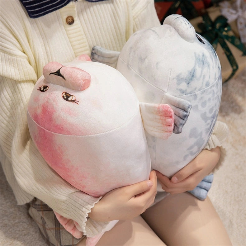 A person holds two ZoDoll Seal Plush Toys—cute, chubby stuffed seal pillows in pink and gray (20cm/40cm)—while sitting on a soft surface.