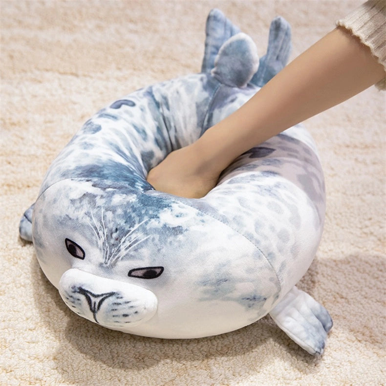 A hand presses down on the ZoDoll Seal Plush Toys Cute Chubby Seal Plush Pillow, a soft 20cm or 40cm gray and white stuffed seal animal, shown resting on a beige carpet.