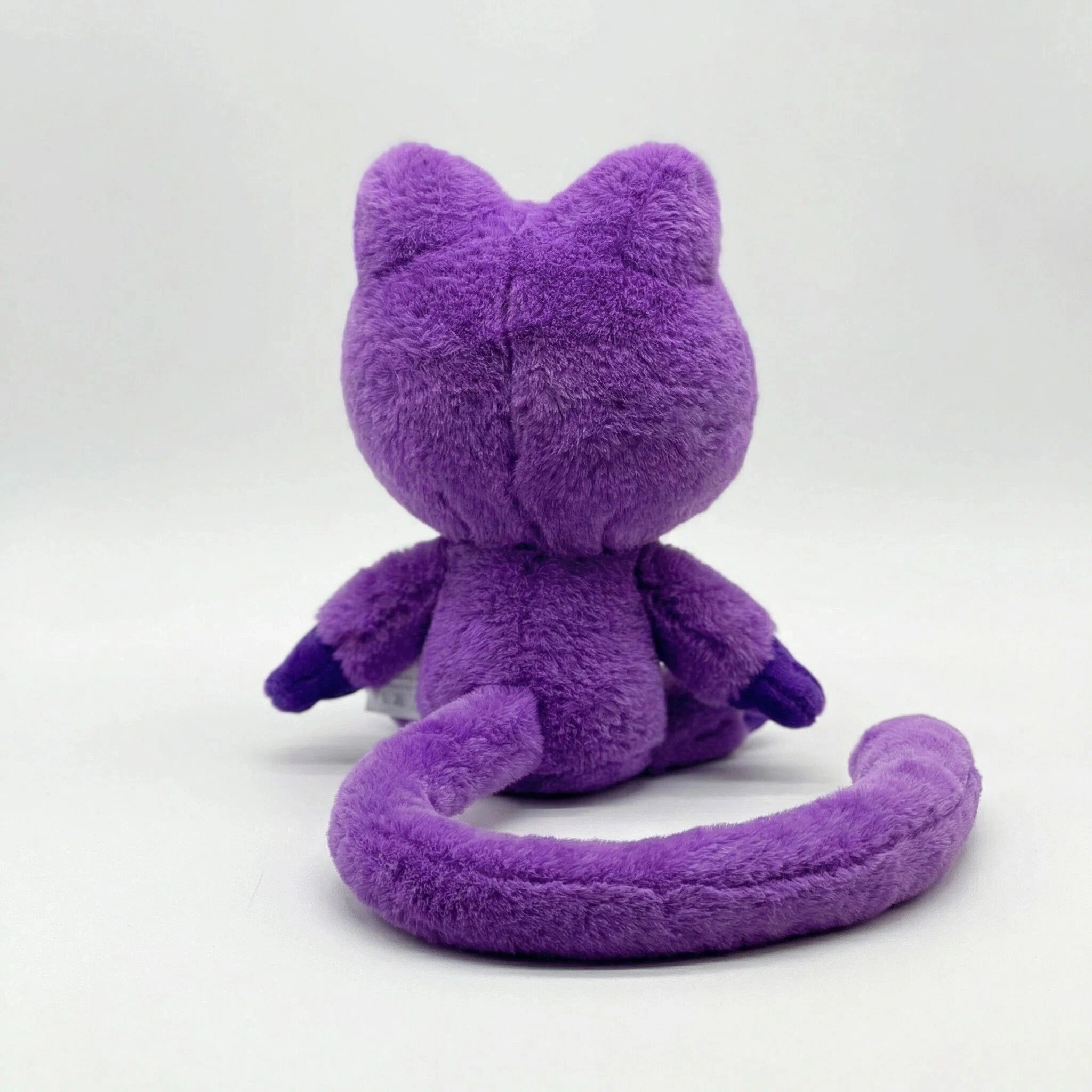 A Poppy Playtime CatNap Plush, shown from the back with its tail curved to the side, sits against a plain white background. Available in 4 styles as part of the Monster & Nightmare CatNap Plush Toys collection.