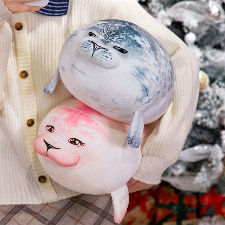 A person in a cream cardigan holds two ZoDoll Seal Plush Toys—soft, cute chubby seal plush pillows (one grey with spots, one pink), 20cm and 40cm sizes—against a blurred background.
