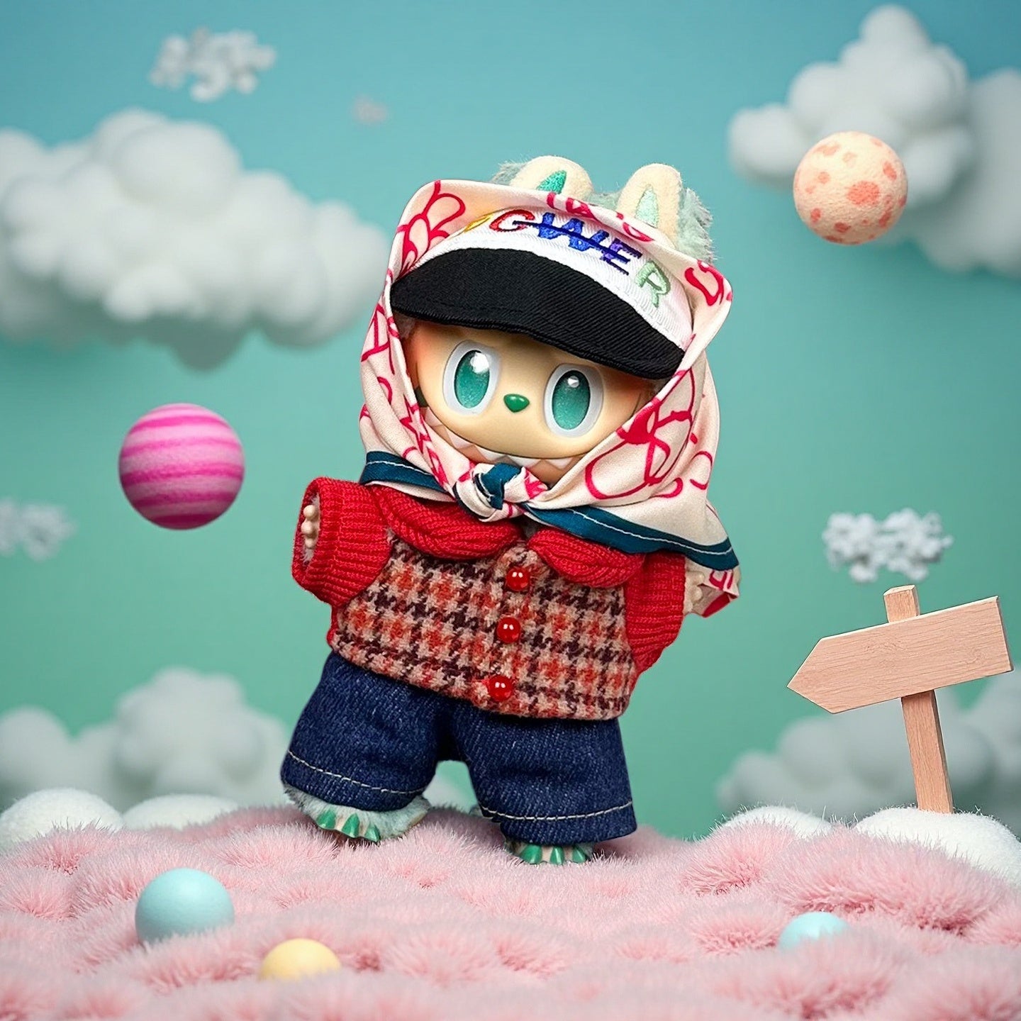 A ZoDoll Labubu Doll wearing a tweed jacket, denim shorts, scarf, and cap 4-piece set stands on a pink furry surface with colorful balls and clouds in the background, its large blue eyes shining.