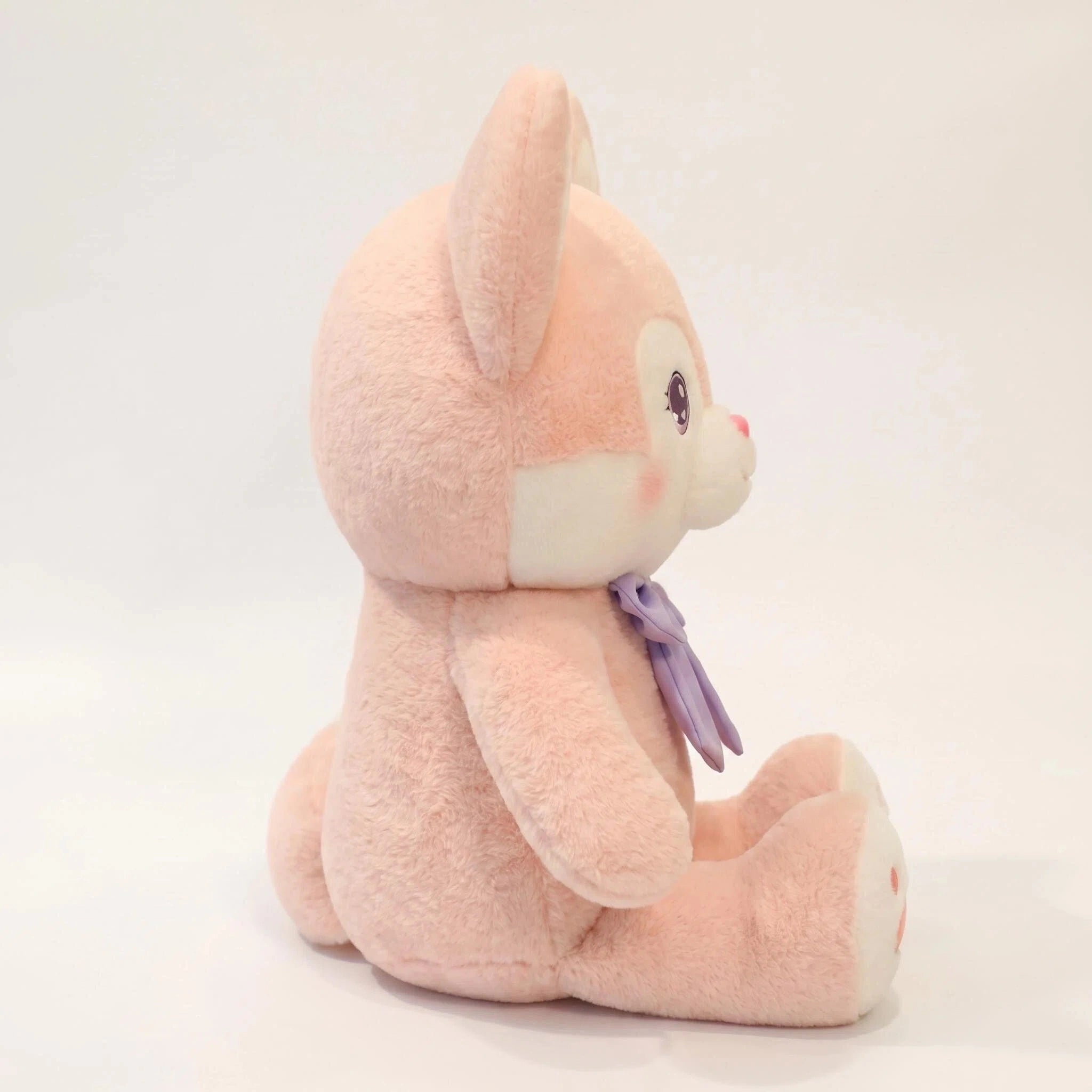 A side view of the ZoDoll Pink Fox Plush—a cute fox doll with a kawaii face, rabbit-like ears, white accents, and a purple bow—sits upright against a plain white background.