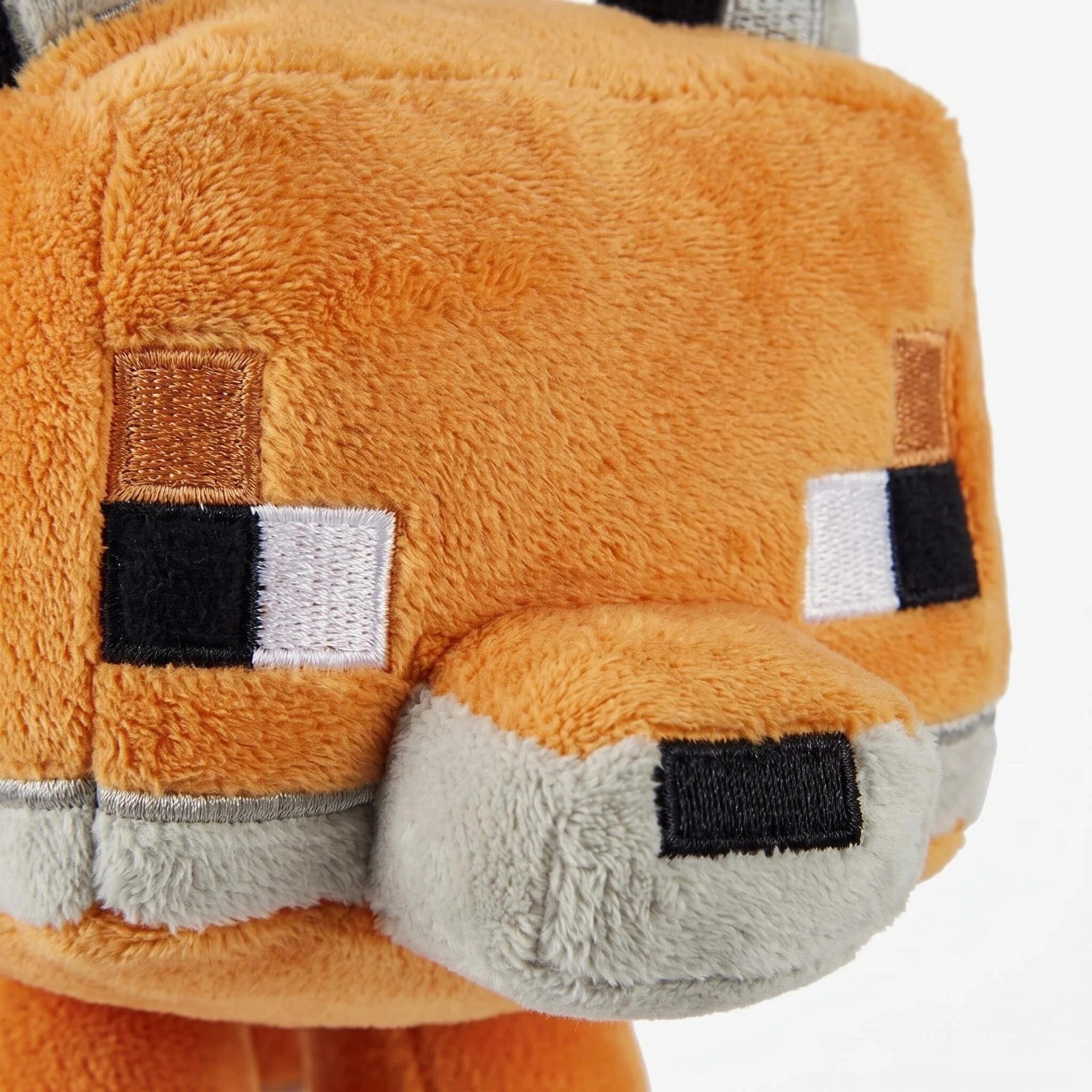 Close-up of the ZoDoll Minecraft Fox Plush—a cute, blocky stuffed animal with orange and gray coloring, plus embroidered eyes and nose.