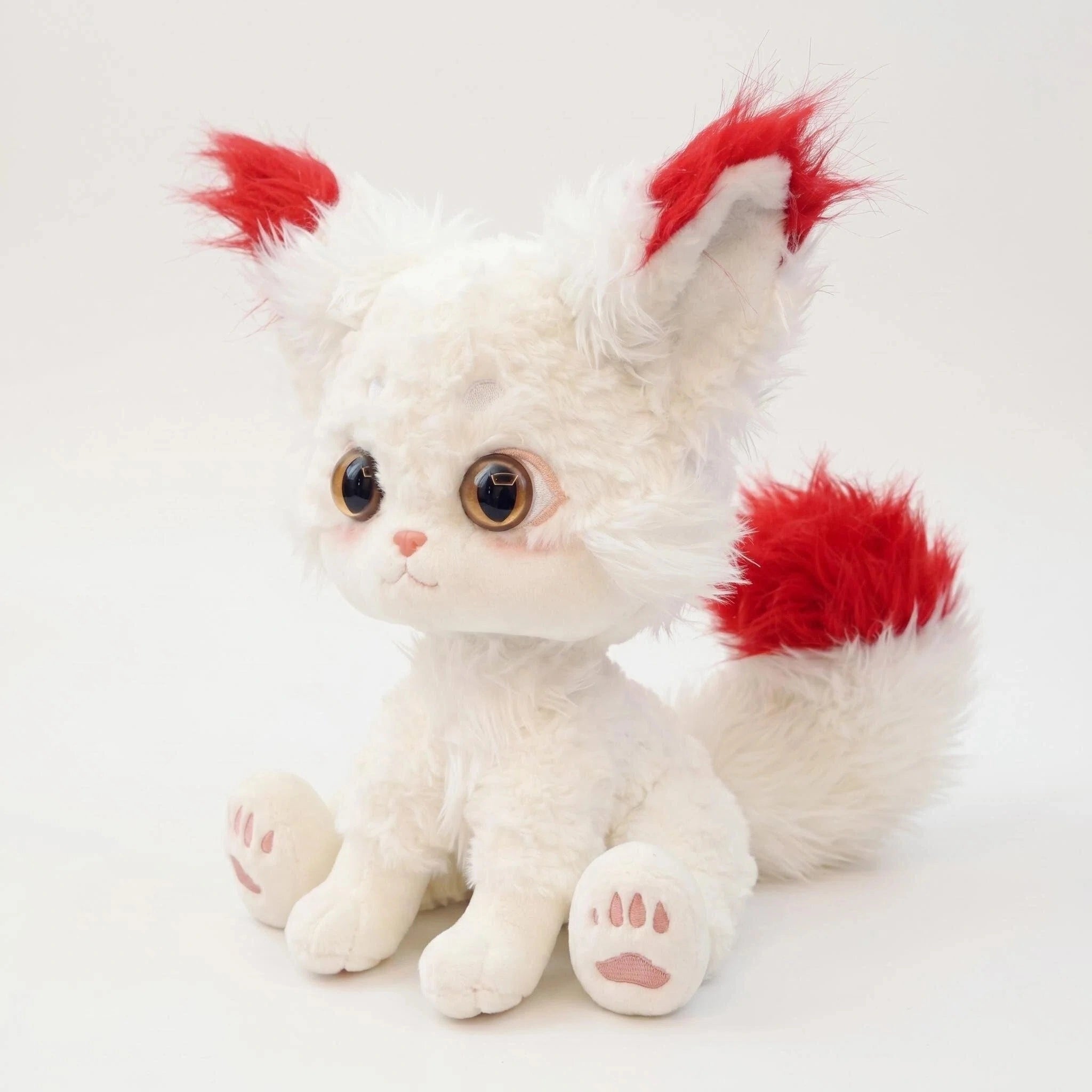 The ZoDoll White Fox Plush Toy is a cute arctic fox stuffed animal with big ears, a fluffy tail, large brown eyes, red-tipped features, and pink paw pads. It sits adorably on a plain white background.